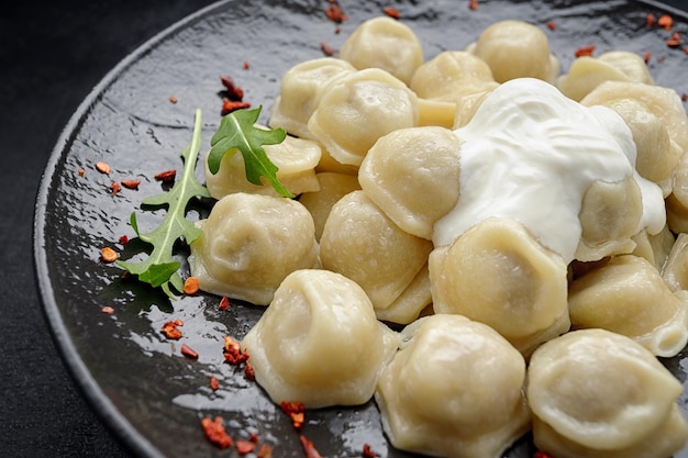 ukrainian-dumplings-with-sour-cream-arugula-black-glossy-plate-dark-background_210632-2945.jpg